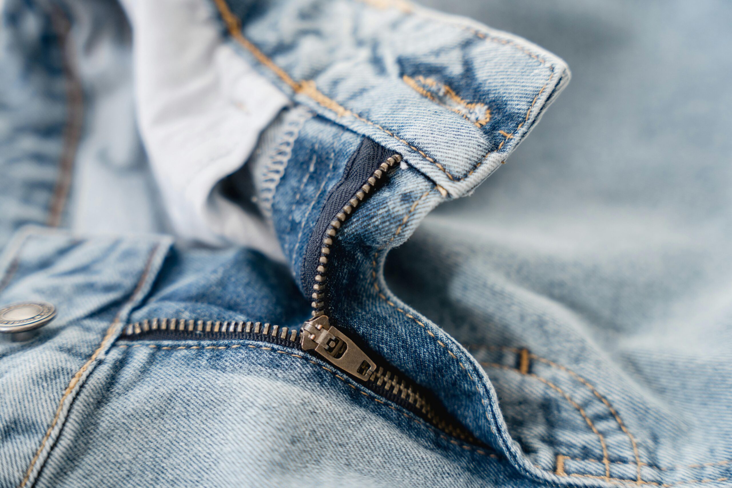 Detailed shot of a blue denim jeans zipper showcasing fashion texture and stitching.